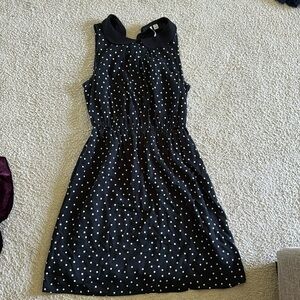 A black polka dot dress with a belt around middle.